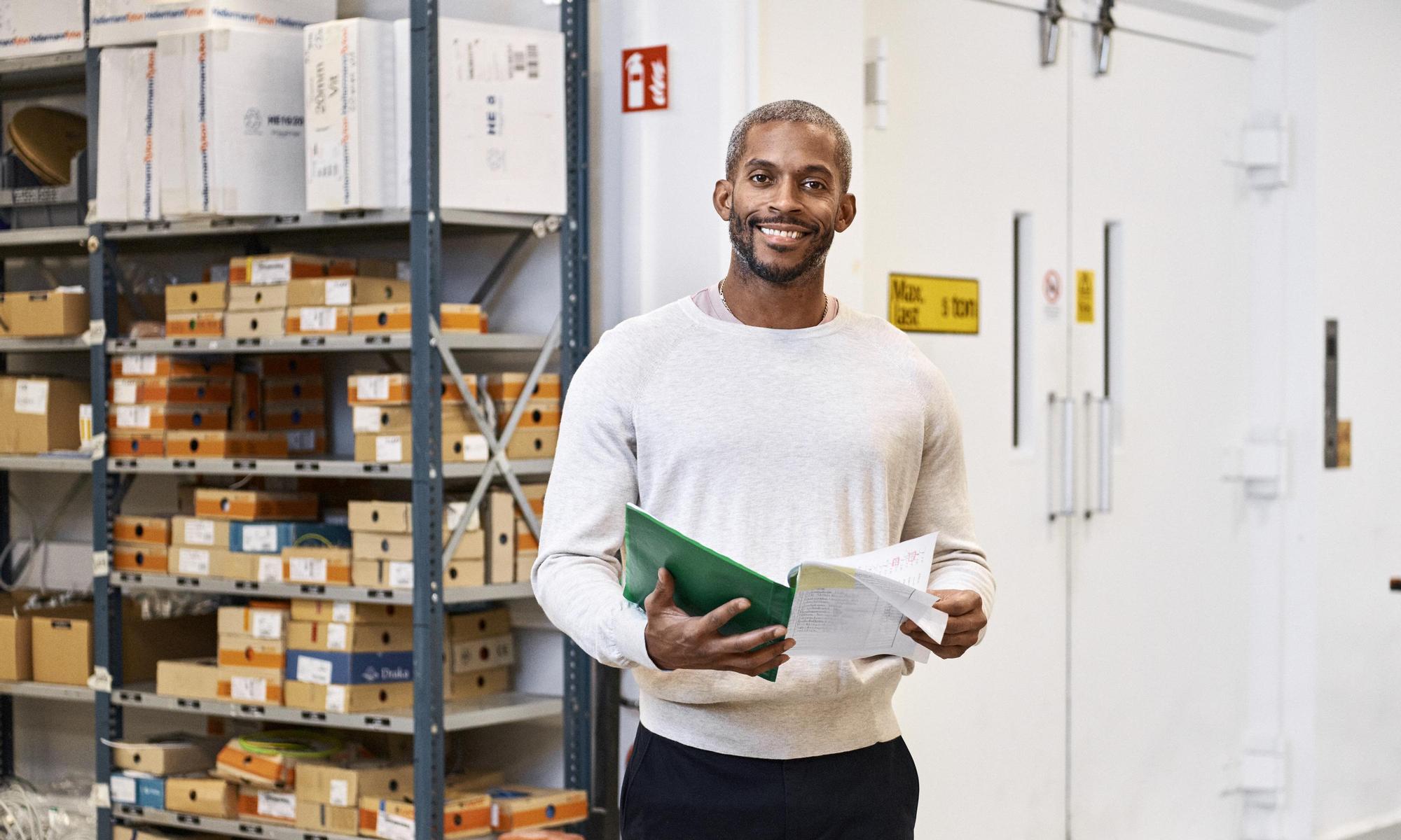 Man at a company holding a folder looking in to the camera