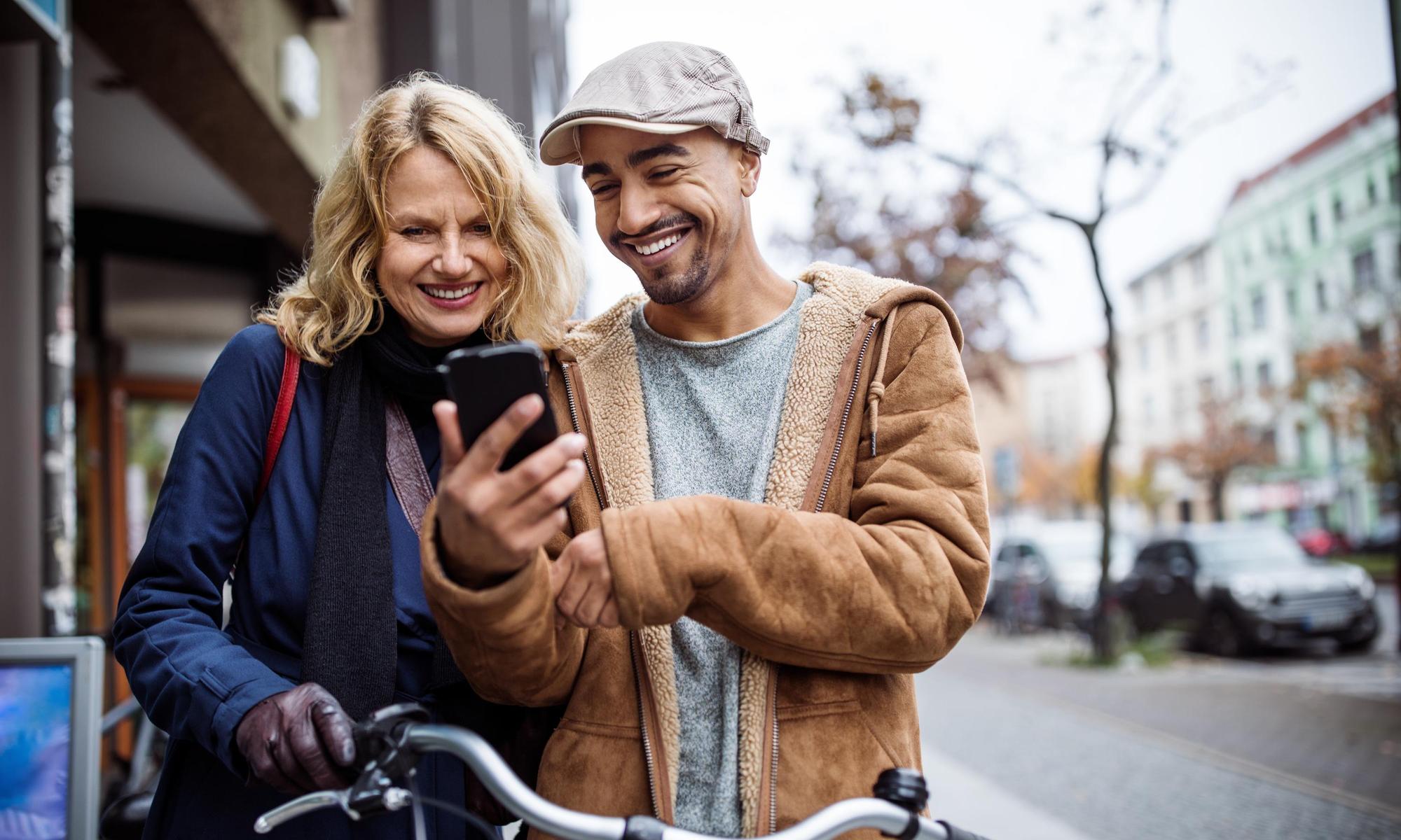 Happy man showing mobile phone to friend