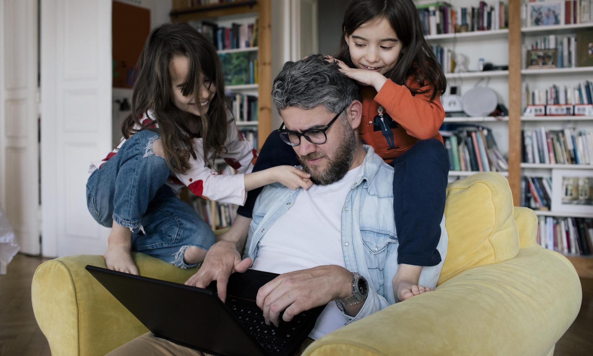 Dad looking at a laptop together with his kids